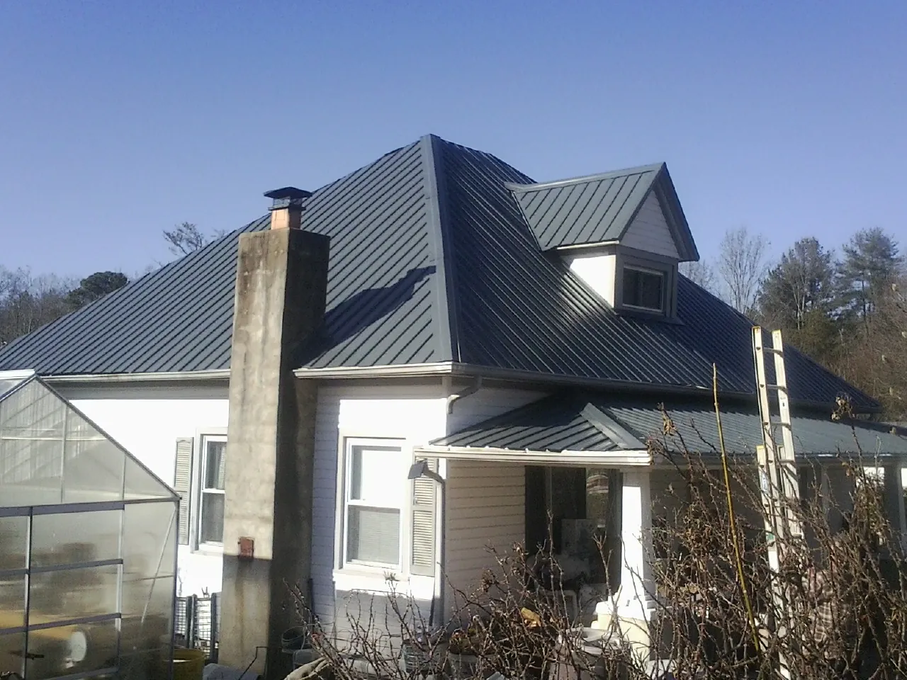 Dark blue standing seam metal roof on a white farmhouse with dormer — Slate & Tile Roof Repair by Roofing Brothers in Mossville
