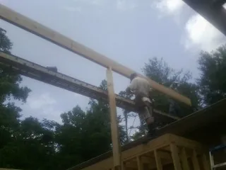 Carpenter setting a ridge beam over a new addition frame — Ice Dam Removal by Roofing Brothers in Mossville