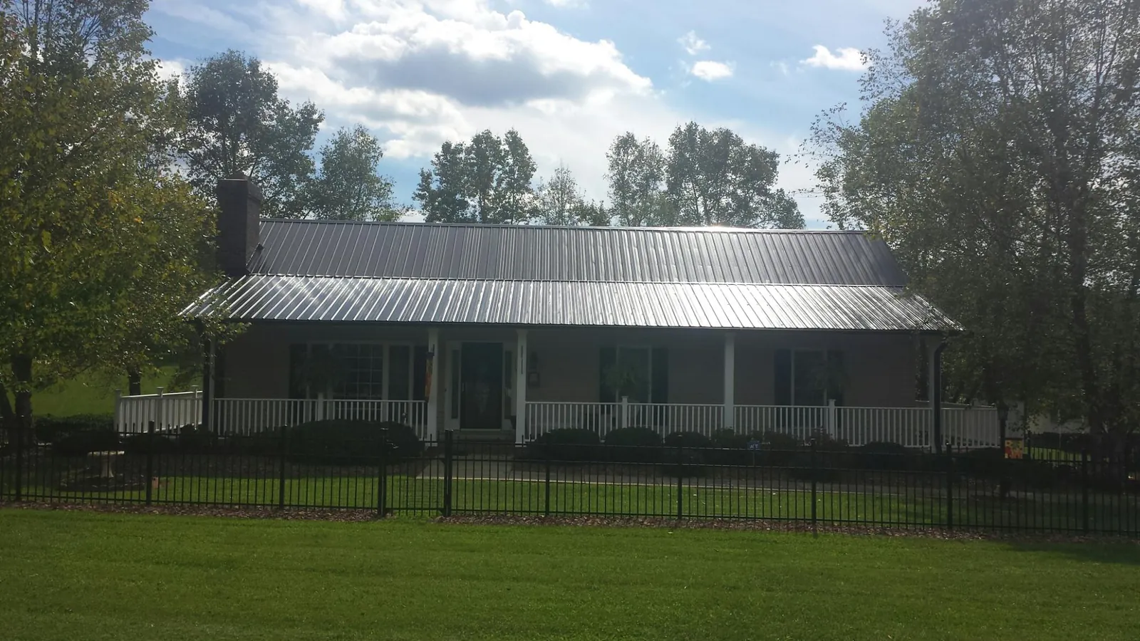 Gray metal roof on a brick ranch with a full width front porch — Gutter Guard Installation work by our crew in Mossville
