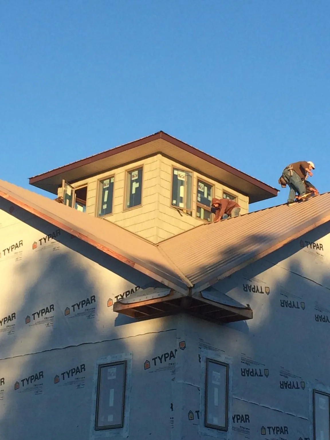 Roofers working around a rooftop cupola on a new metal roof at sunset — Roof Waterproofing in Mossville by Roofing Brothers